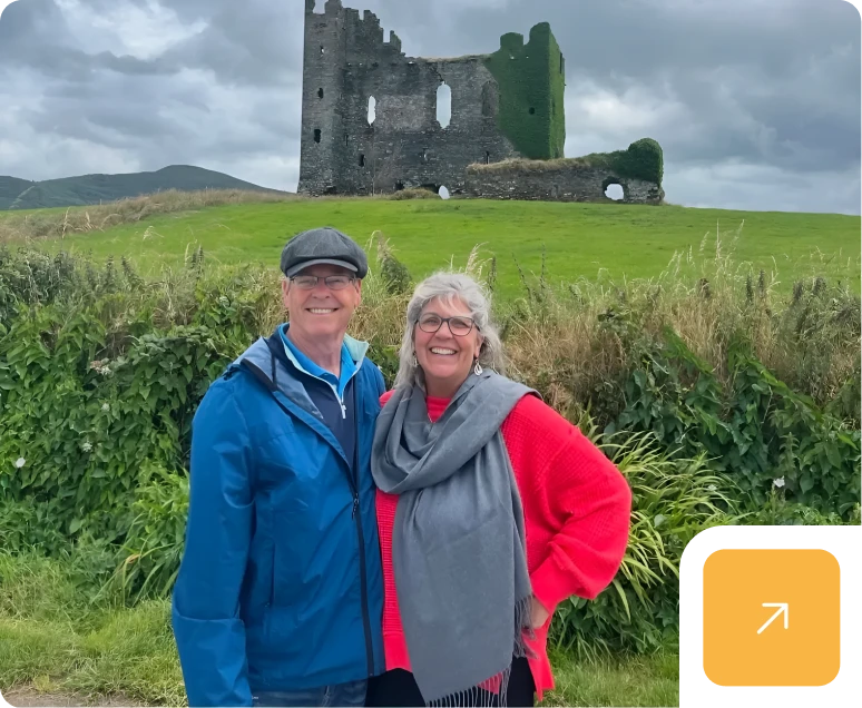 Couple smiling in front of ancient castle ruins.