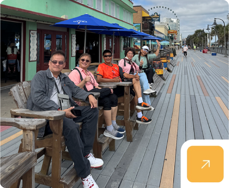 Group seated on boardwalk benches with Ferris wheel